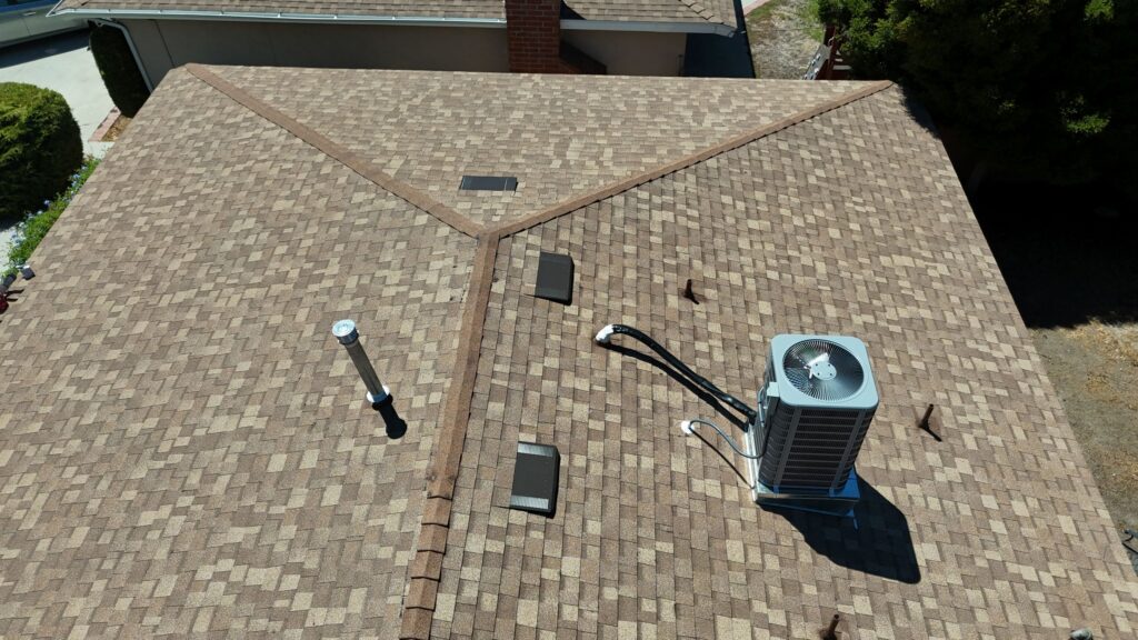 Energy-efficient roofing in Simi Valley featuring solar-reflective shingles, ventilation pipes, and an air conditioning unit, demonstrating sustainable home improvements.