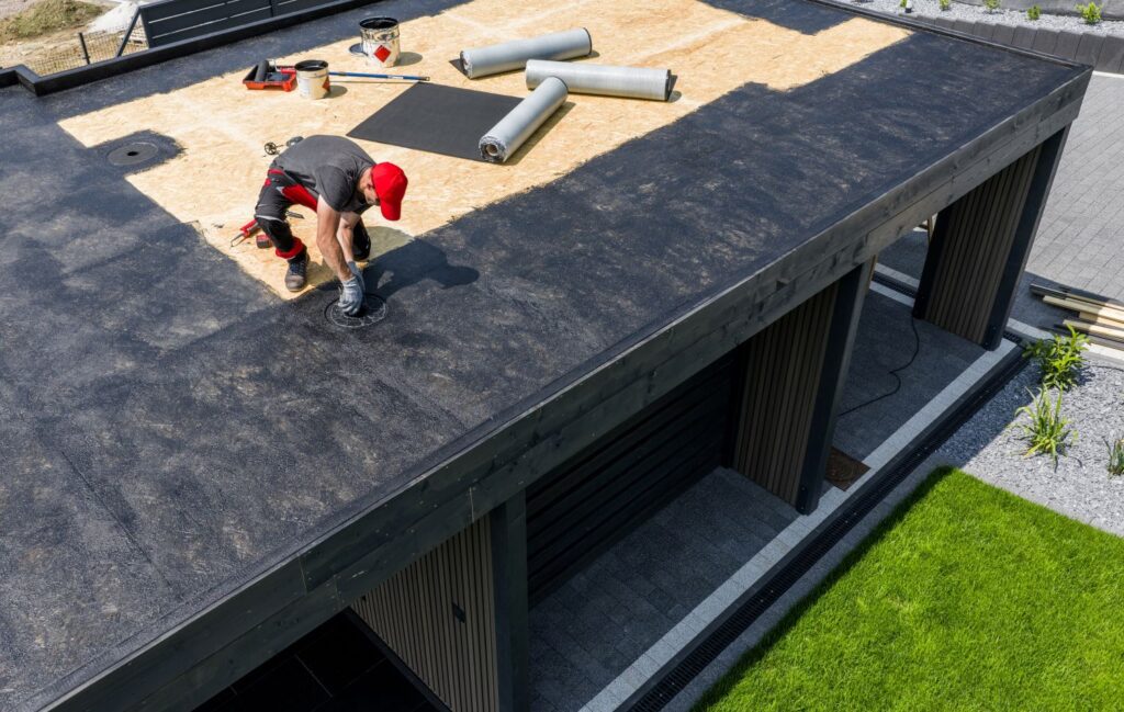 Construction worker applying EPDM roofing material on a flat roof, showcasing low-slope roofing techniques and quality craftsmanship.