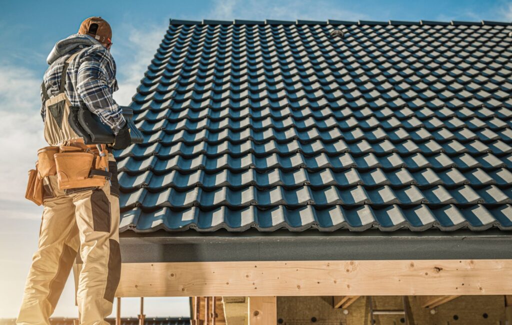 Roofing contractor inspecting newly installed blue tile roof, showcasing craftsmanship and quality roofing materials.