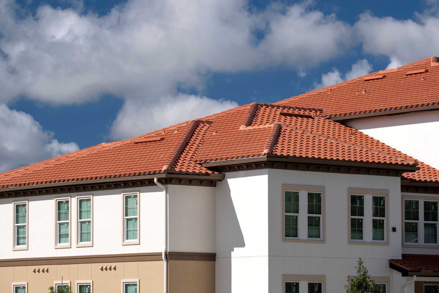 Tiled roof covering a modern condo building in Florida, showcasing terracotta roof tiles against a bright blue sky with clouds, emphasizing durable roofing options.
