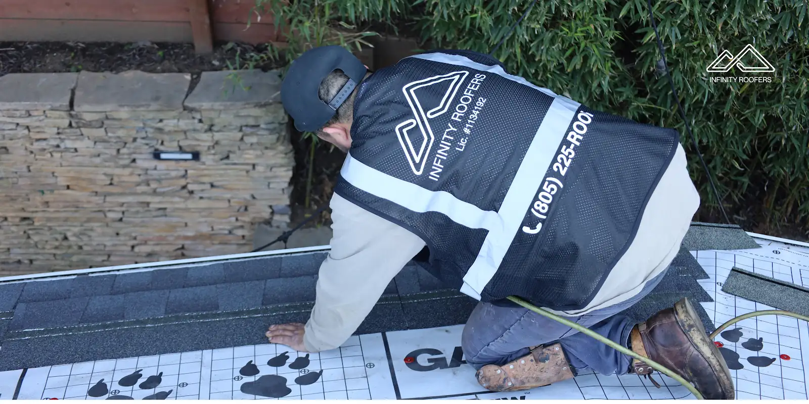 Infinity Roofers roofer setting new shingles next to a stone chimney