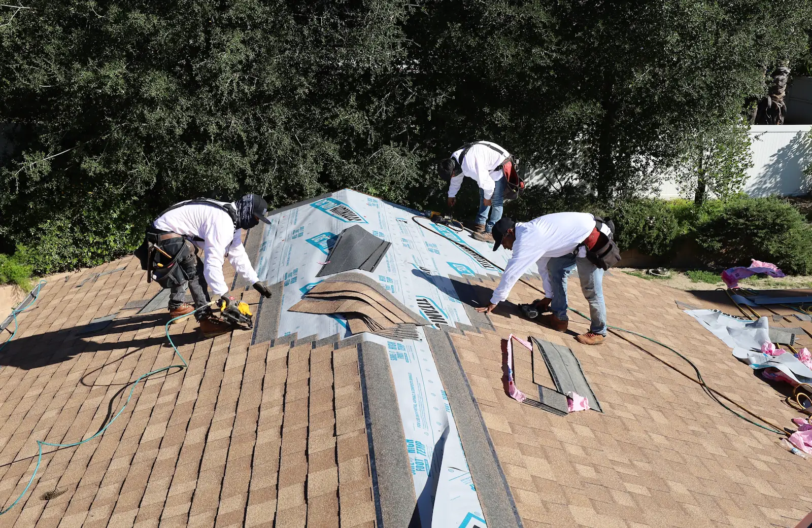 Infinity Roofers roofers repairing a shingle roof around a hip and valley