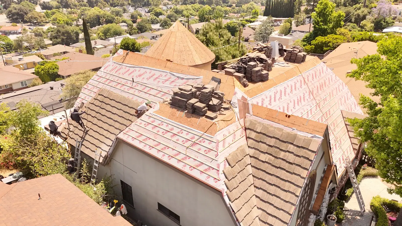 Infinity Roofers crew relaying concrete tile over new underlayment during a roof replacement