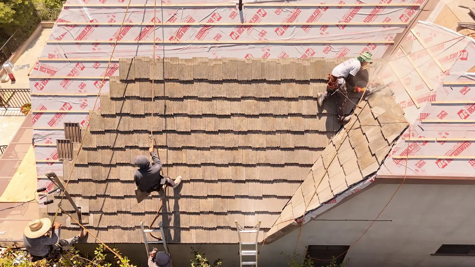 Infinity Roofers crew relaying concrete tile over new underlayment and battens, seen from above