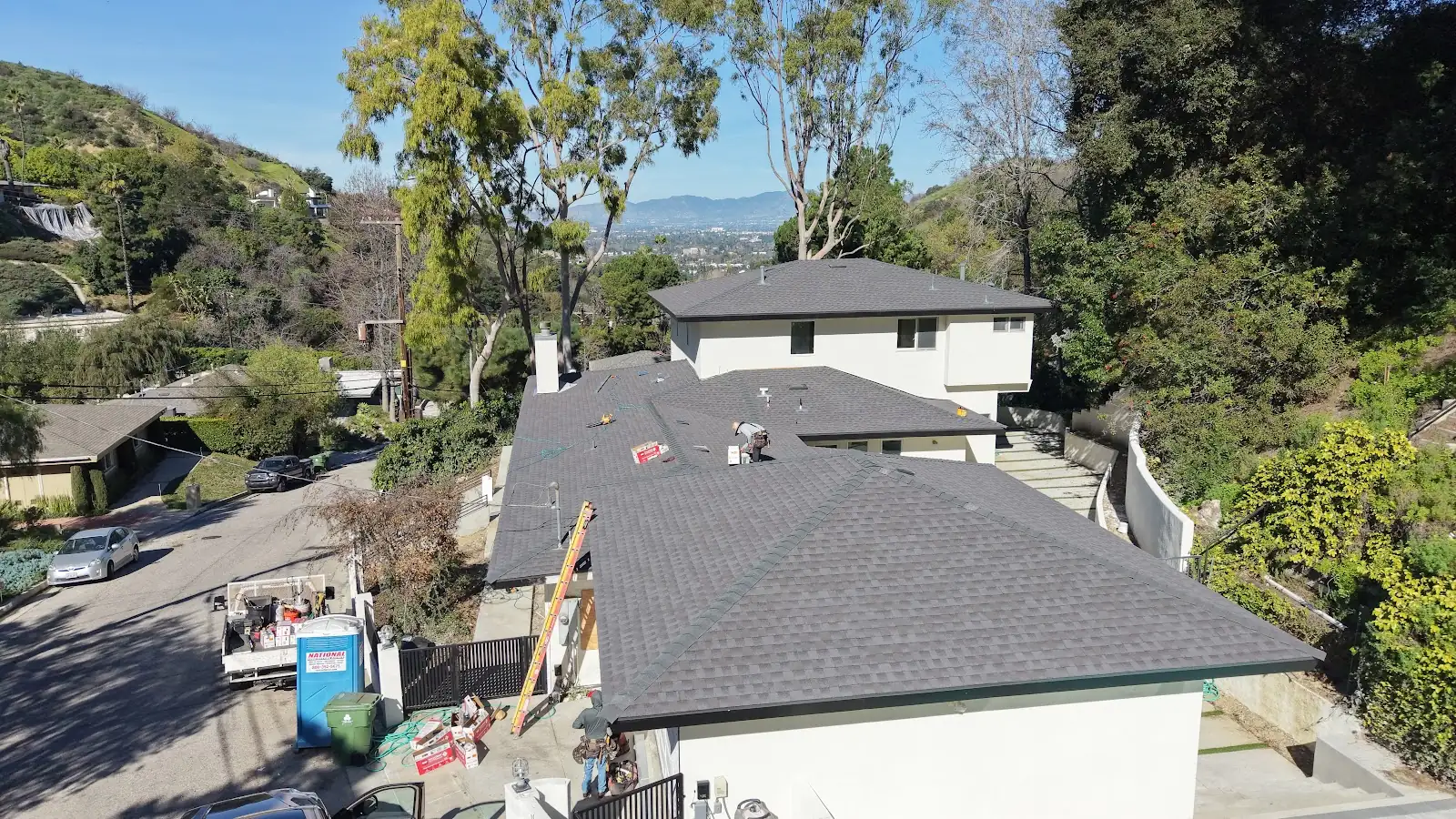 Shingle roof replacement on a hillside home by Infinity Roofers, aerial view